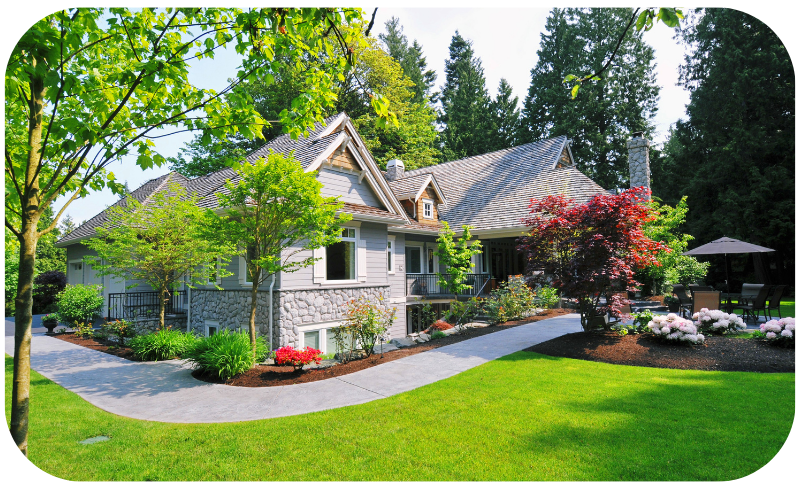 A beautiful white house with green yard and well maintained landscape.